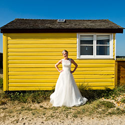 a bride against a yellow beach hut in Mudeford